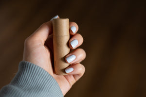 Hand holding capped cardboard peppermint lip balm tube