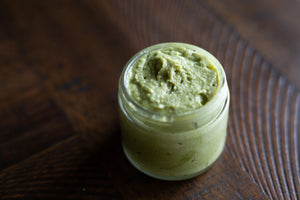 Uncapped glass jar of green matcha mint sugar scrub