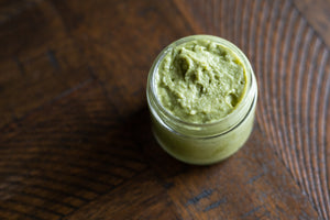Top view of uncapped jar of green matcha mint sugar scrub