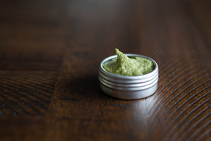 side angle of uncapped metal tin of green matcha mint sugar scrub in 1/2 oz size